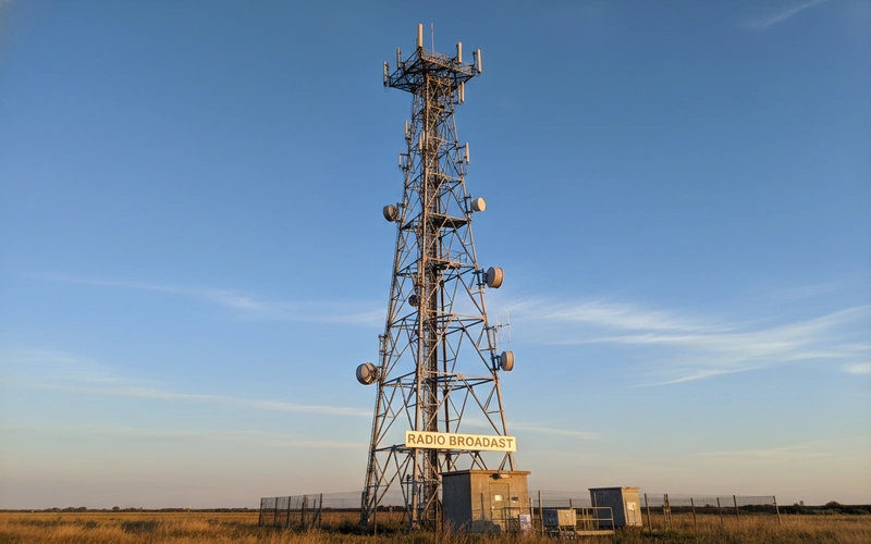 Tall FM broadcasting antenna tower with mounting equipment against clear sky